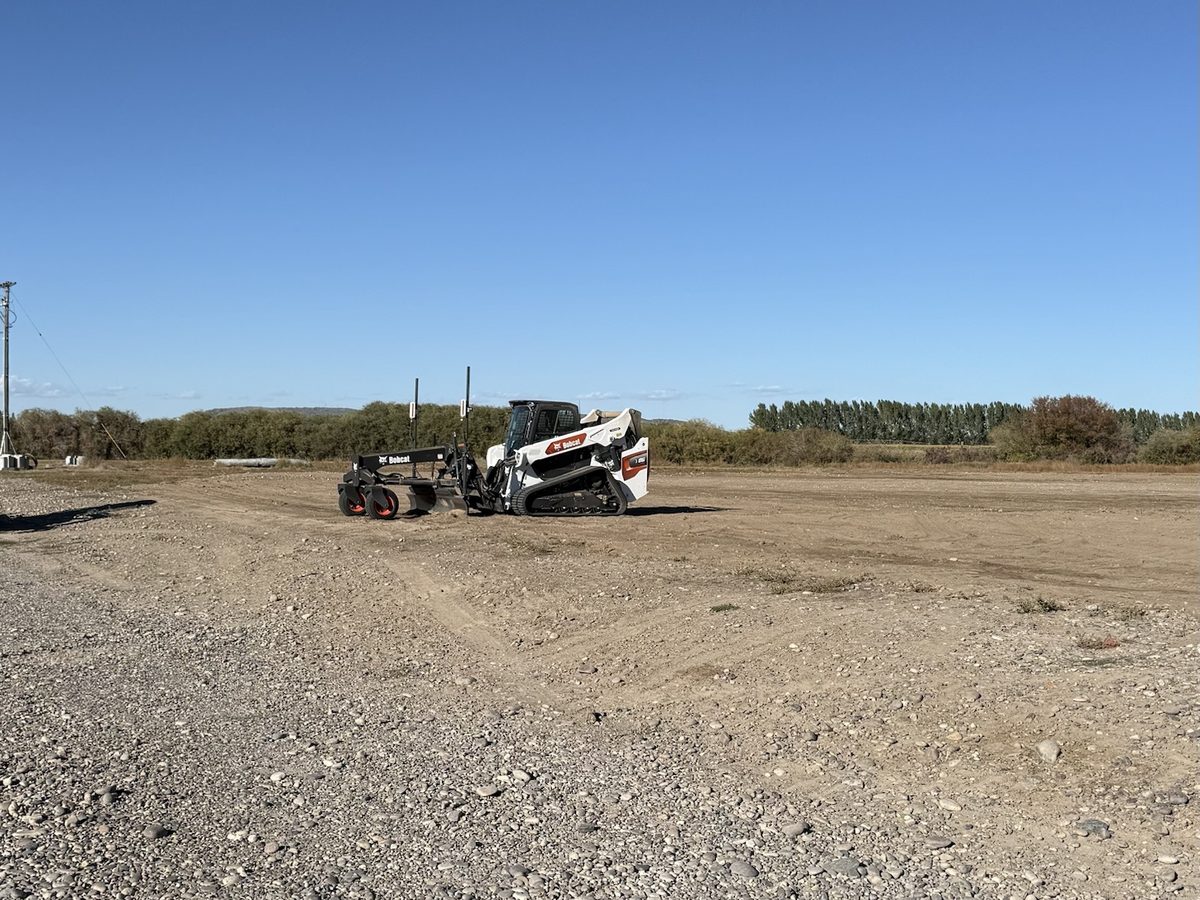 Skid steer with a laser grader working a large lot in East Idaho